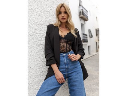 Modelka má na sebe elegantný dámsky komplet so sakom a nohavicami v modernom strihu.