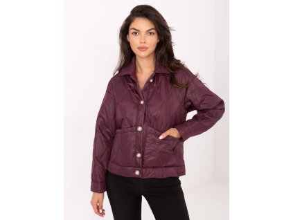 Modelka má na sebe dámsku prešívanú prechodnú bundu s ozdobnými gombíkmi v elegantnom strihu.