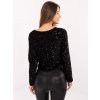Modelka má na sebe čiernu elegantnú flitrovanú blúzku s ozdobnou mašľou, ideálnu na večerné a spoločenské udalosti.