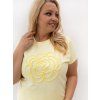 Modelka v plus size tričku s kvetinovou aplikáciou.
