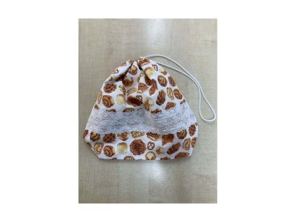 Fehér, péksütemény mintás kiscipós zsák csipkedíszítéssel, összehúzható zsinórral a világos faasztalon