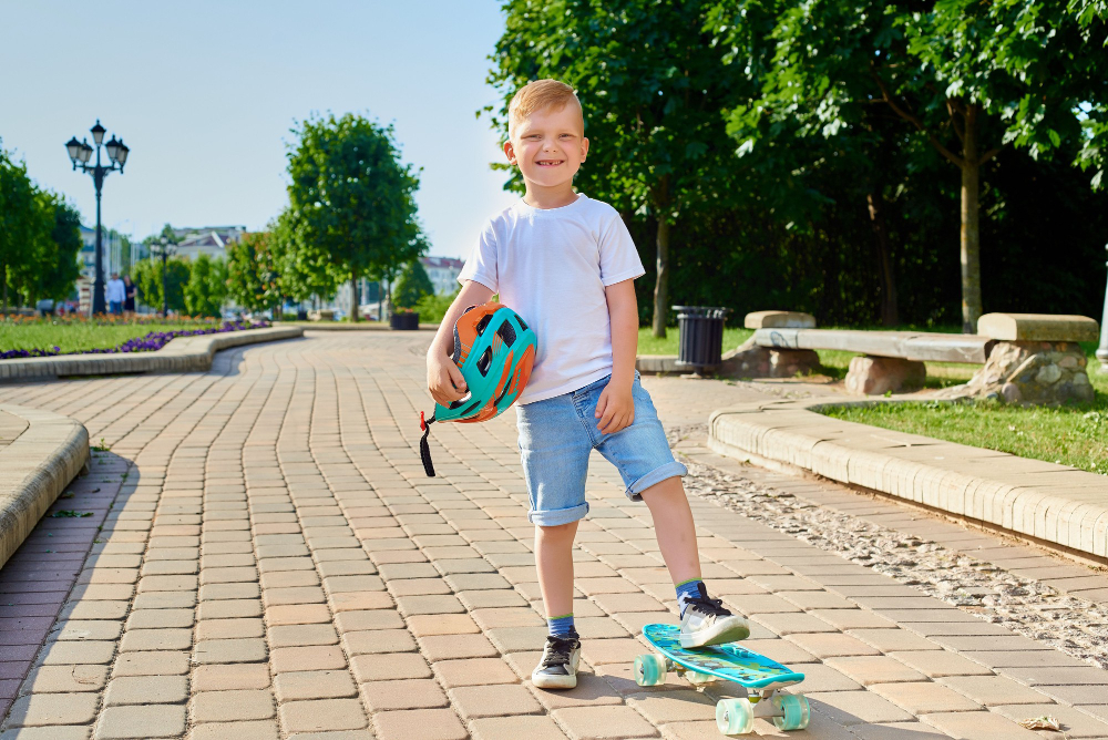 Chlapec se skateboardem a helmou stojí připraven na jízdu v parku