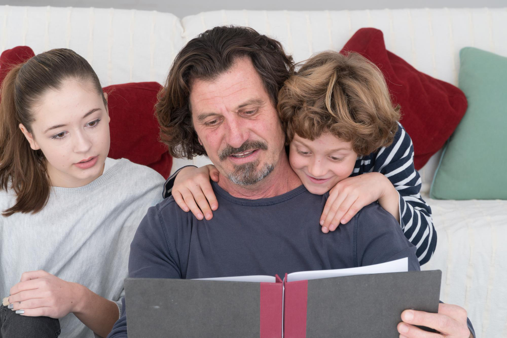 Táta se dvěma dětmi sedí na gauči a společně probírají šachovou strategii