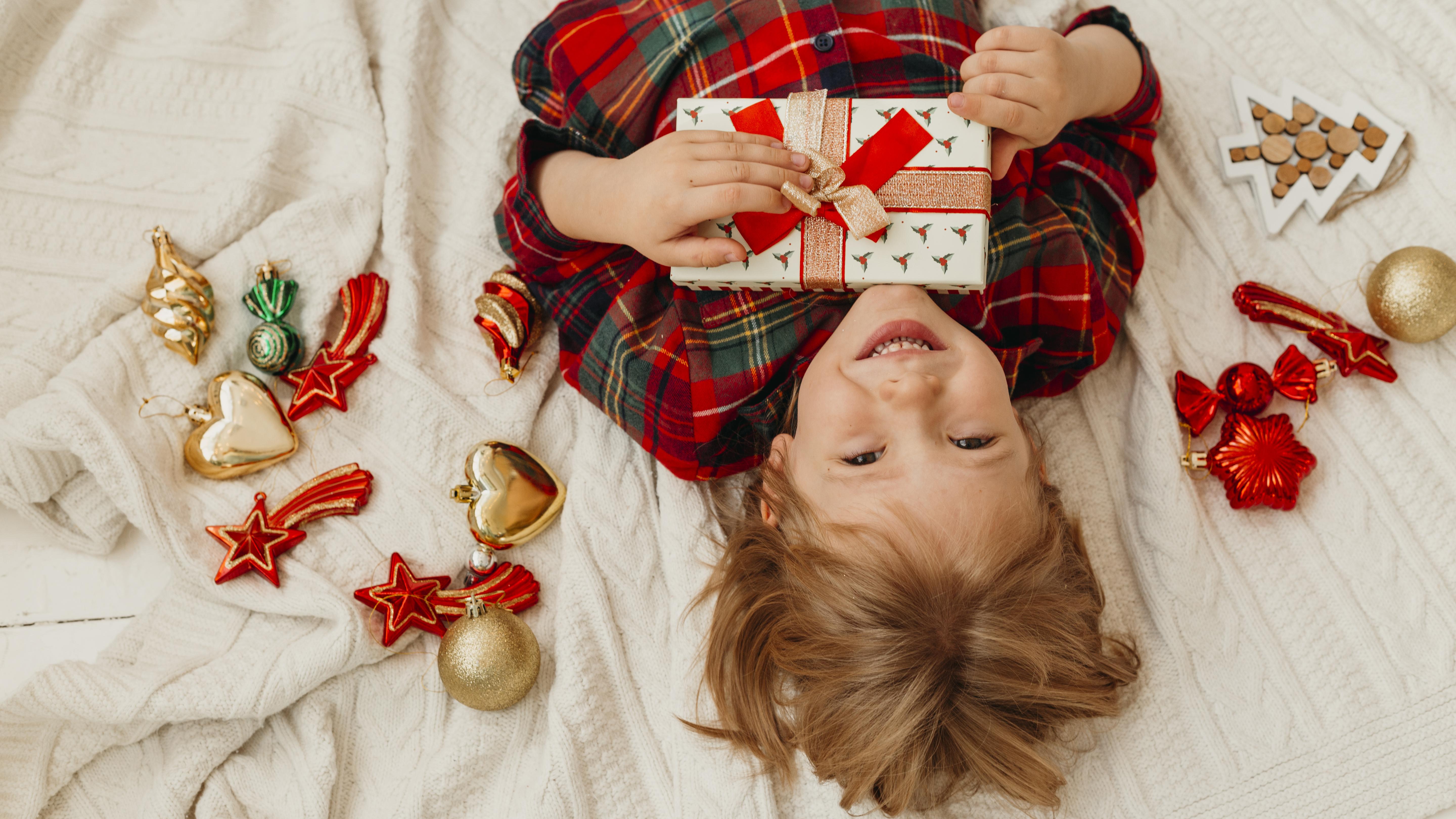 top-view-child-holding-a-christmas-gift-in-bed