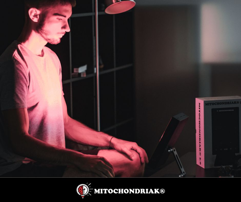 Man using Mitochondriak red light therapy panel at desk for targeted session