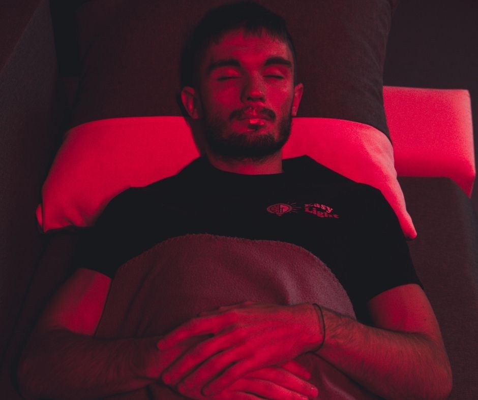 Man lying down during red light therapy session for better sleep