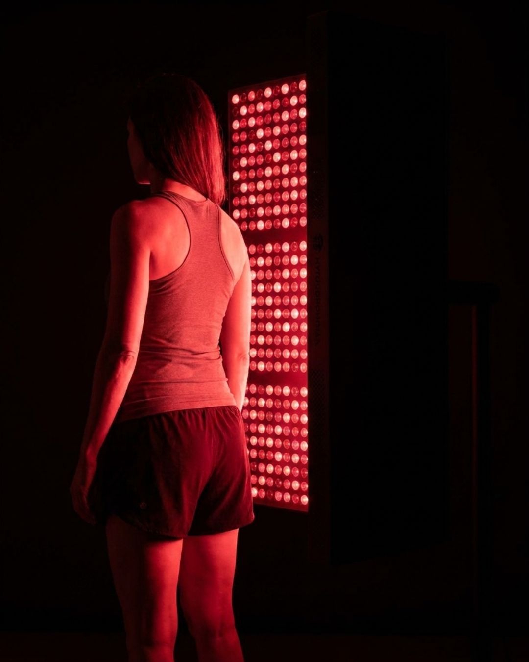 Woman using Maxi panel for full-body red light therapy and weight loss support
