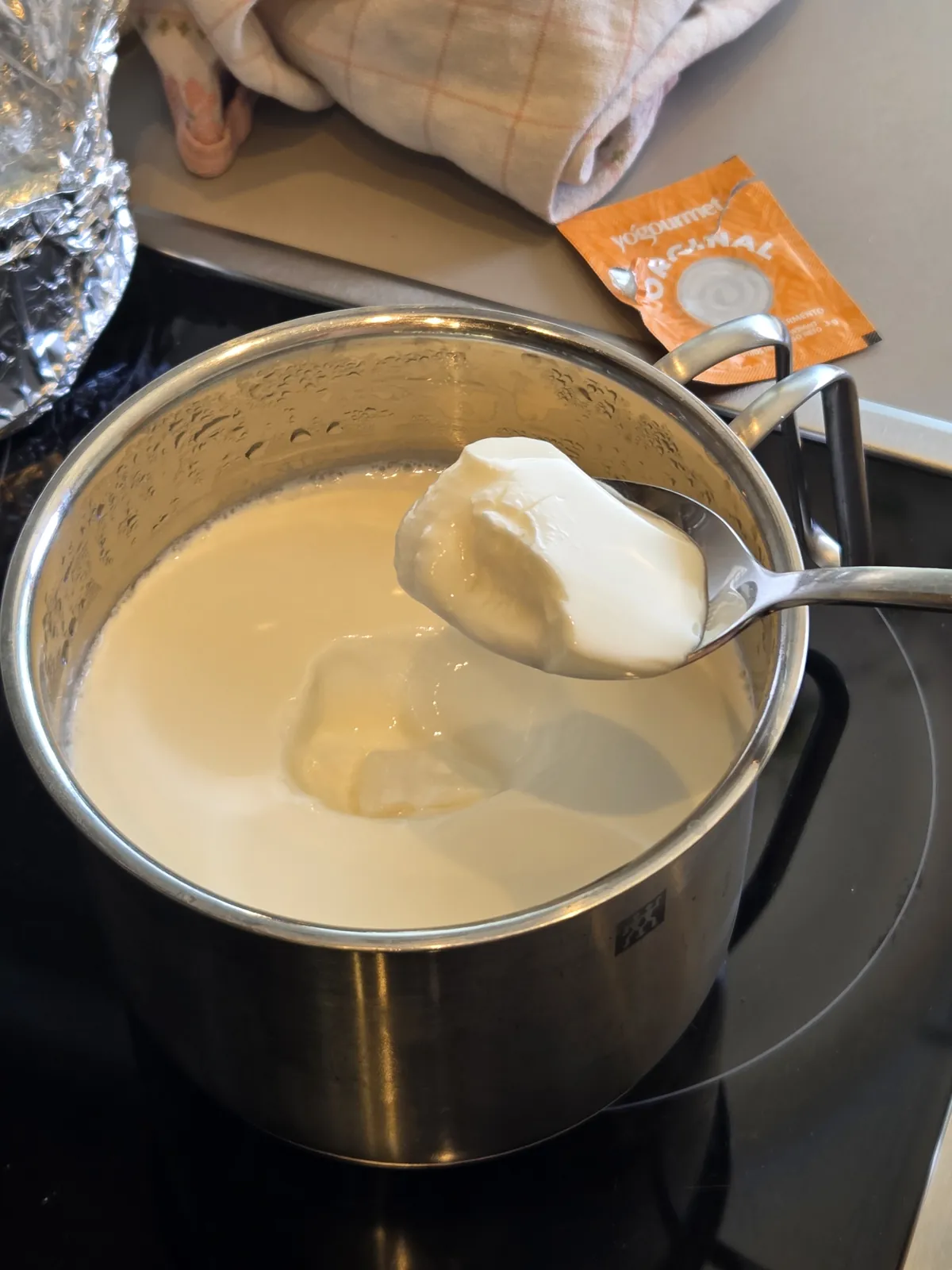 Hotový domáci biely jogurt na lyžici, hustá porcia s čistým lomom po vychladení v chladničke