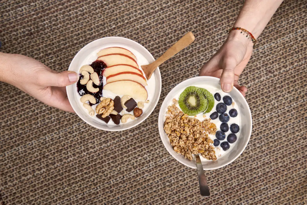 Dve misky domáceho bieleho jogurtu s rôznou oblohou: jablko, orechy a čokoláda v jednej, granola, kiwi a čučoriedky v druhej