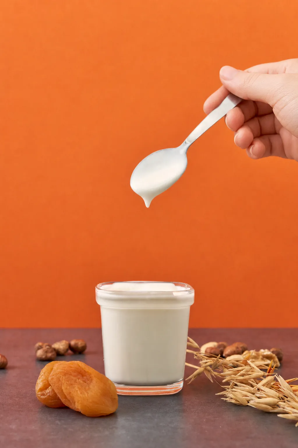 Domáci biely jogurt v sklenenom pohári a lyžička s hustým krémovým jogurtom