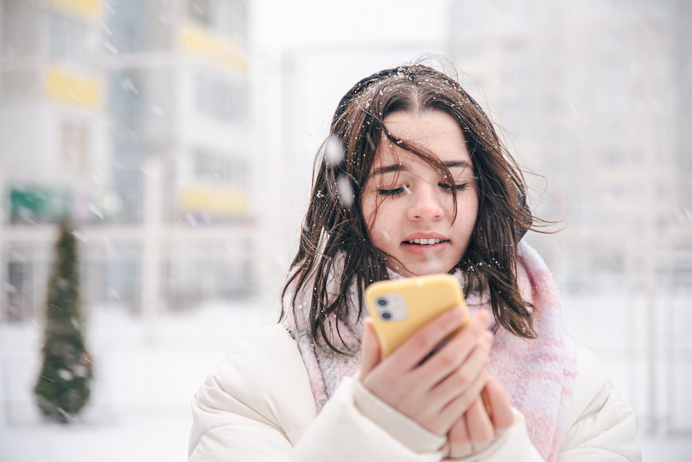 portrait-teenage-girl-outdoors-with-smartphone-snowy-winter-weather