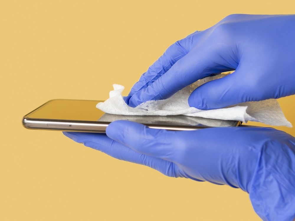 side-view-hands-with-surgical-gloves-disinfecting-smartphone