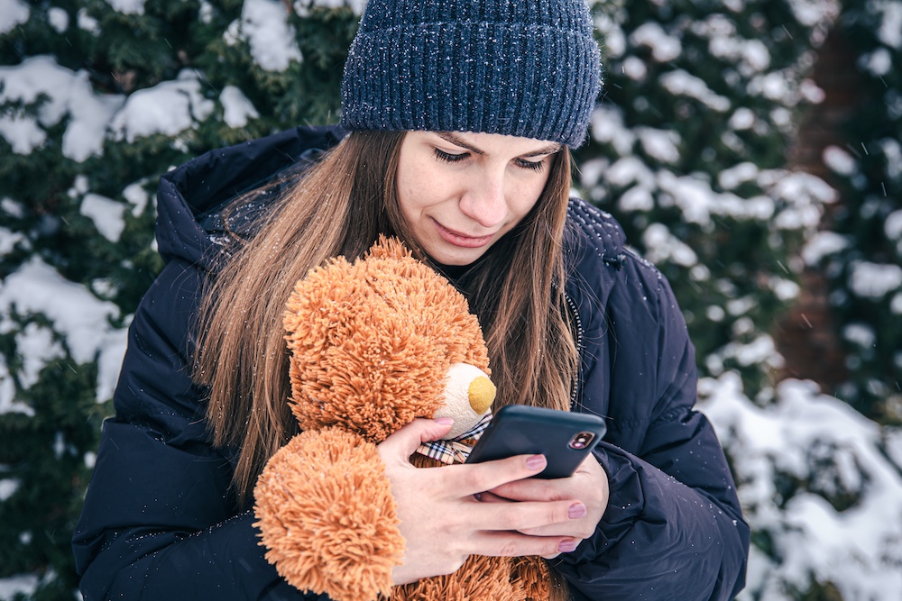 young-woman-holds-teddy-bear-smartphone-her-hands-snowy-weather