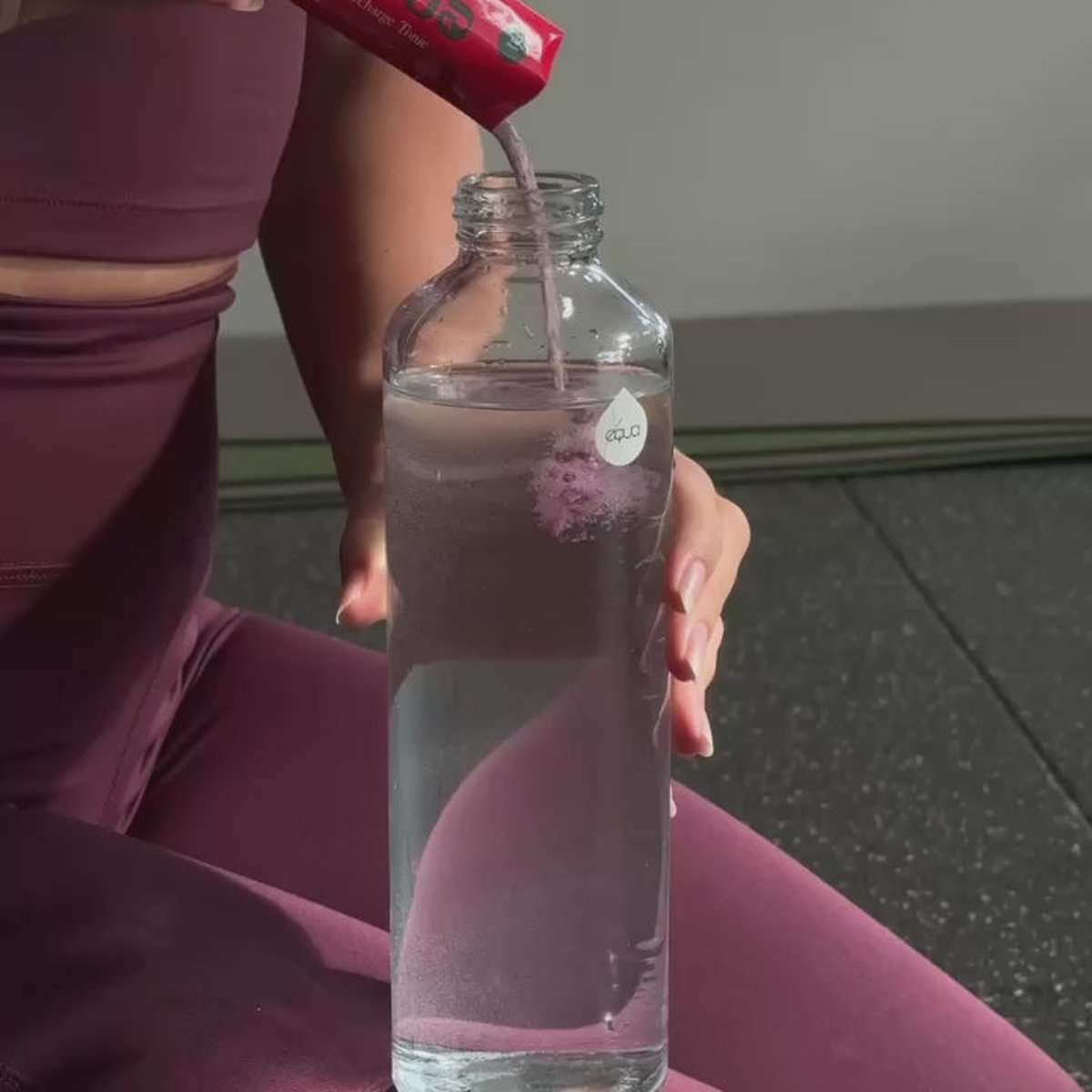 Žena ve sportovním oblečení s lahví Recharge Tonic