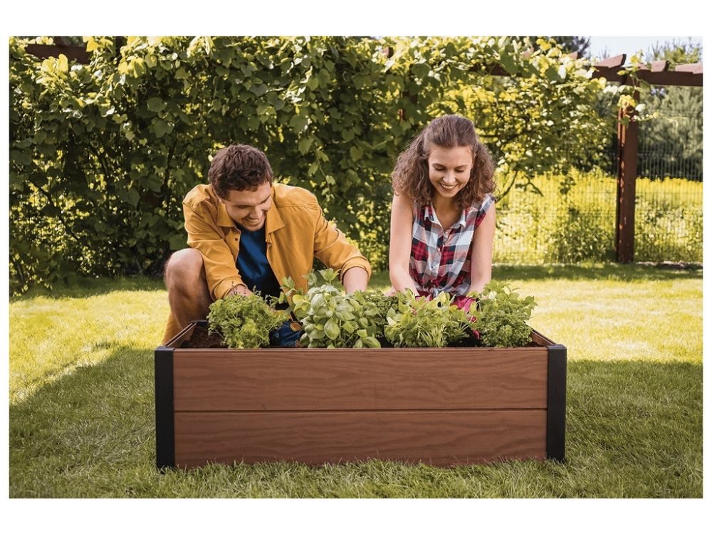 mladý pár sadí bylinky do vyvýšeného záhonu