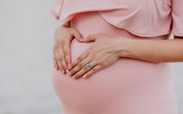 Žena v pokročilém stádiu těhotenství držící si bříško