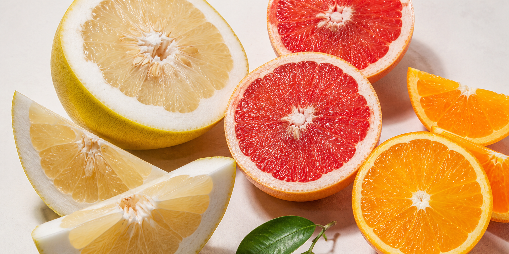 Pomelo, grep a pomeranč ve světlé flatlay kompozici