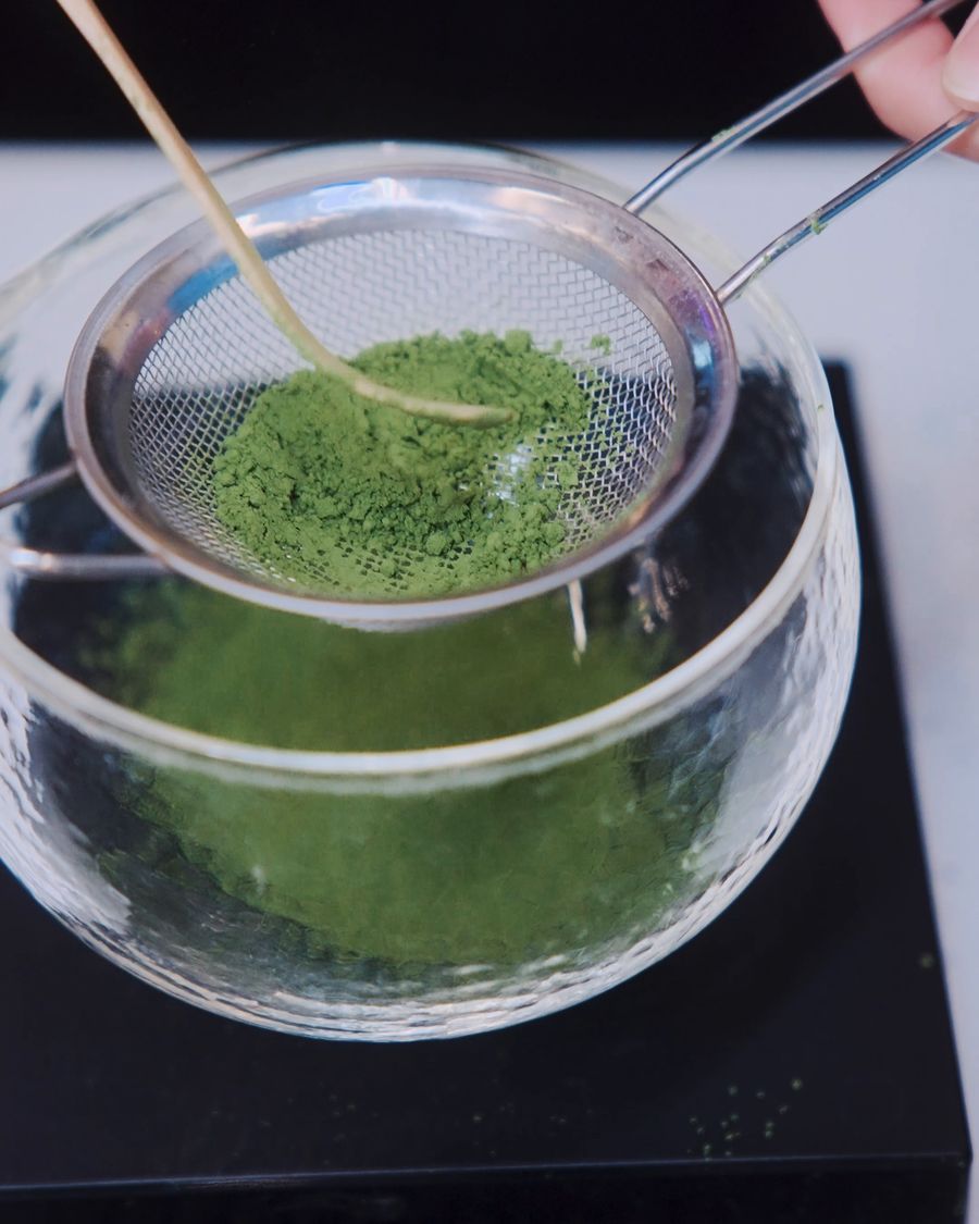 Matcha prosívaná sítkem do skleněné misky.
