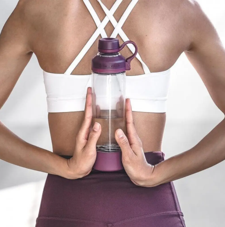 žena v športovom s fľašou BlenderBottle v ruke 