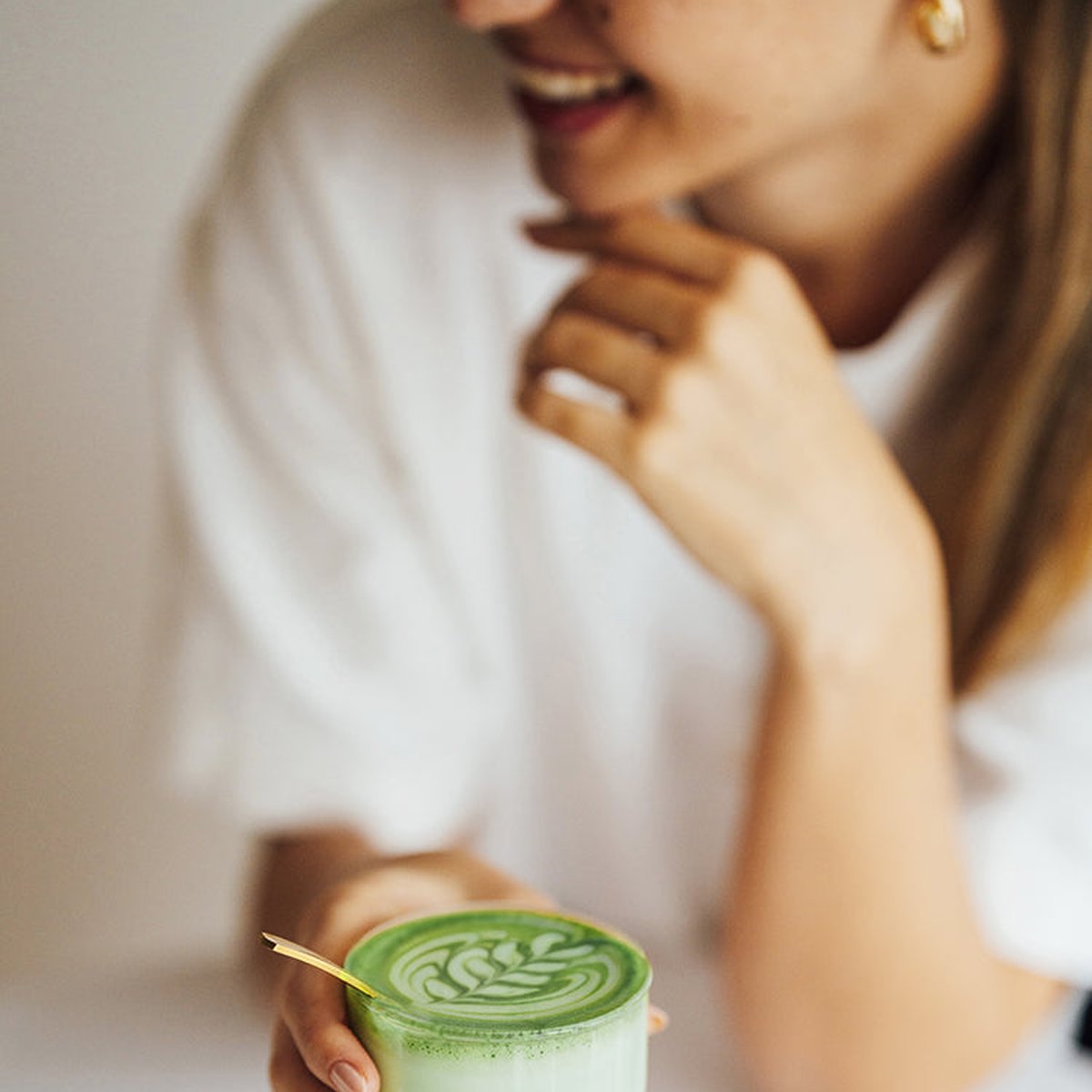 Uśmiechnięta kobieta trzyma szklankę matcha latte