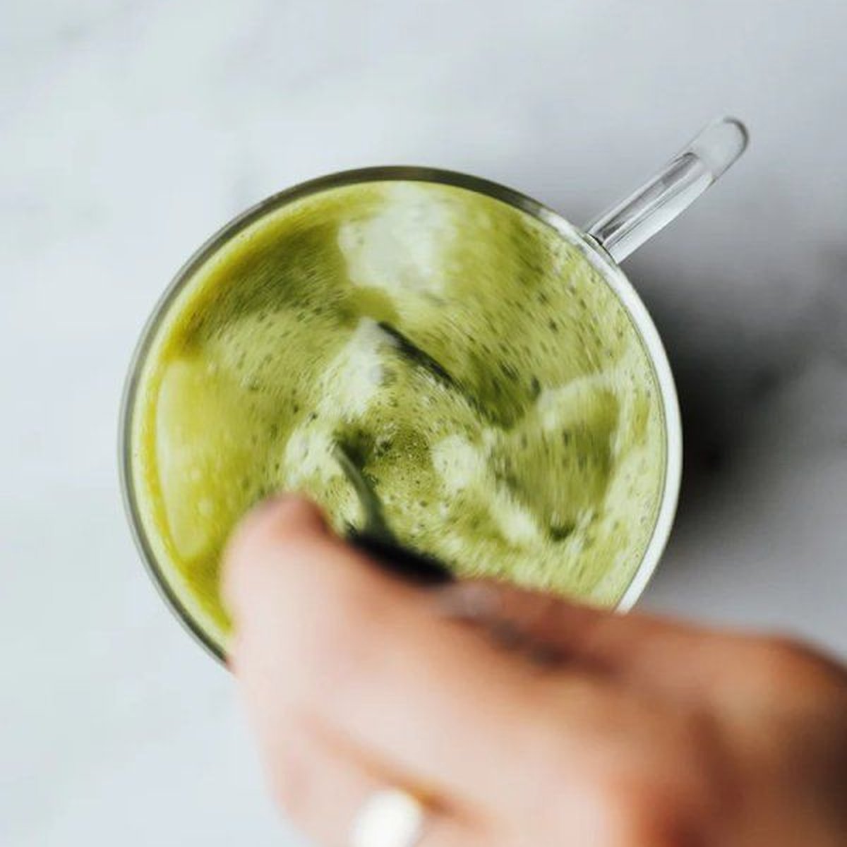 Dłoń trzyma szklany kubek EQUA z matcha latte