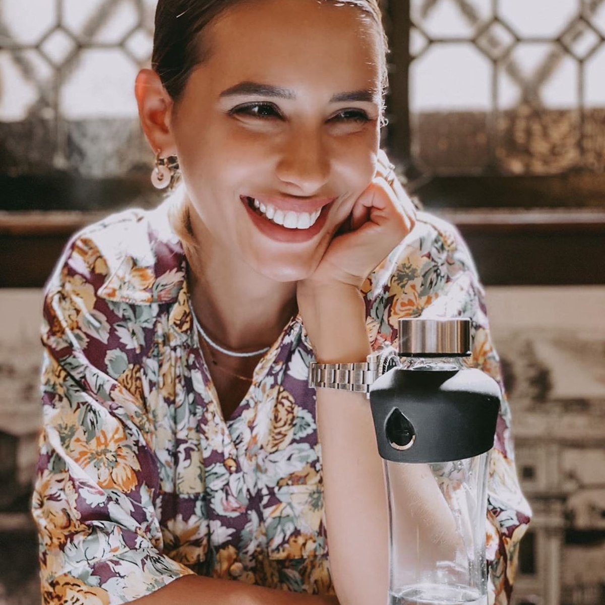 Uśmiechnięta kobieta ze szklaną butelką EQUA Active Black