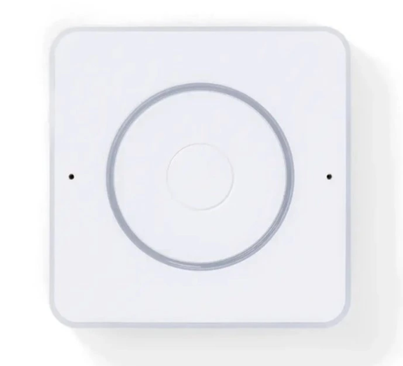 Home Assistant Voice Preview Edition z horního pohledu, čtvercové bílé zařízení s velkým kruhovým ovládacím prvkem uprostřed a dvěma malými otvory mikrofonů po stranách