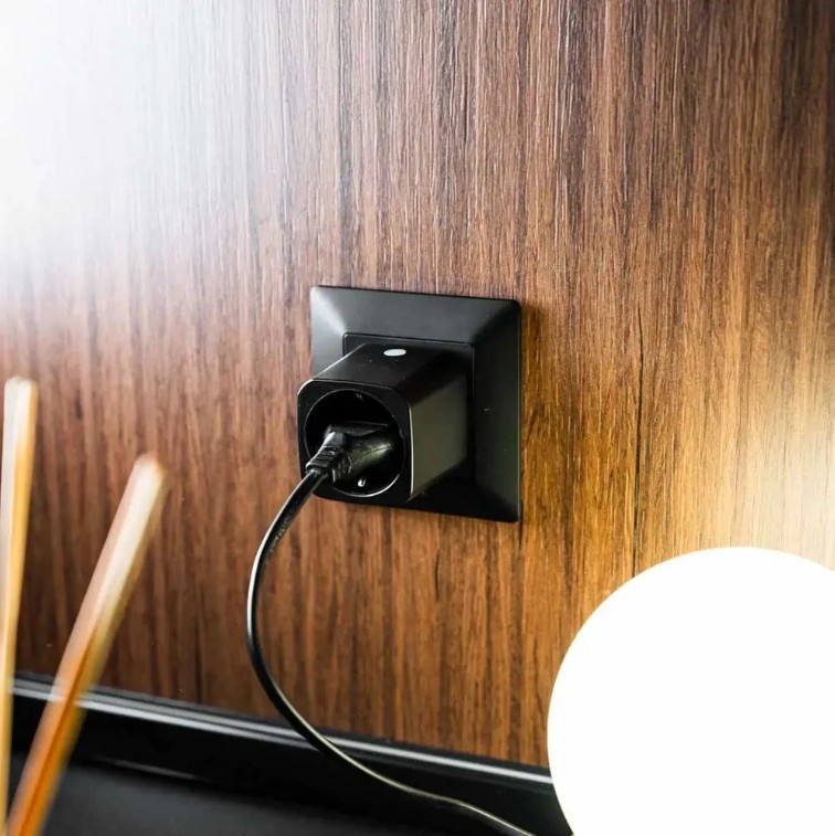 Shelly Plug M Gen3 zapojená v nástěnné zásuvce a napájející připojený elektrický spotřebič.