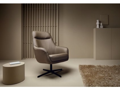 Relaxační kožené křeslo v interiéru, otočná kovová podnož