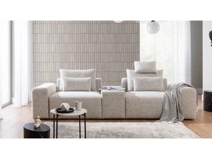 Pohovka LUNA SOFA 2 (1,5BL + PANEL + 1,5BP) ve světle krémovém provedení v obýváku, pohled zepředu se stolkem, lampou a dekou.