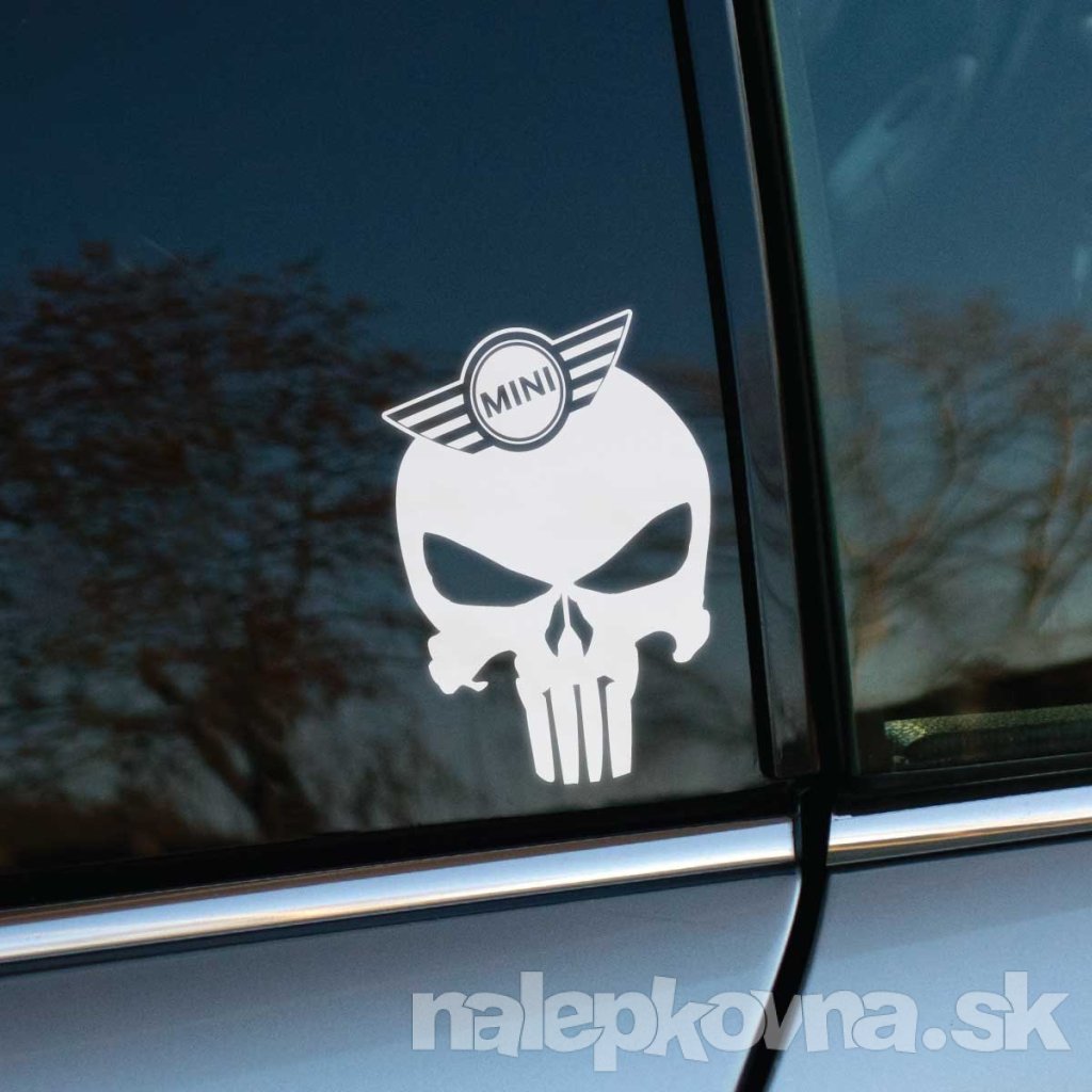 Na fotografii je detail automobilu značky Mini, ktorý zdobí biela nálepka s dizajnom lebky inšpirovanej postavou The Punisher. Lebka je doplnená logom Mini, ktoré je umiestnené v hornej časti. Táto nálepka pridáva autu výrazný a neprehliadnuteľný vzhľad, čím zvýrazňuje športový a rebelsky štýl majiteľa. Skvelá voľba pre tých, ktorí chcú svojim vozidlám Mini dodať osobitý charakter a originalitu.
