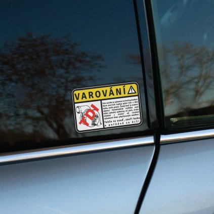 Vtipná nálepka na auto s textom „Varování!“ v žltom rámčeku, ktorá upozorňuje na výkonný turbomychadiel poháňaný technológiou TDI. Text pod varovaním hlási: „Toto vozidlo je vybaveno turbomychadlem, které enormně zvyšuje plnící tlak a dělá kadla, kadla pouuu. Černý kouř je znakem výkonu! Nedostatečné zajištění osob může způsobit spláchnutí od pásů, ztrátu oblečení a slintání od vzrušení způsobené tímto přeplňovaným vozidlem. Takže se usaď, zavři hubu a pořádně se drž!“ Nálepka je nalepená na okne strieborného auta a dodáva vozidlu charakteristický a zábavný vzhľad. Perfektná pre fanúšikov dieselových motorov, ktorí chcú s humorom vyjadriť svoju lásku k TDI technológii a zároveň varovať pasažierov pred intenzívnym zážitkom z jazdy.