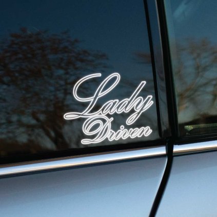Plotrovaná nálepka s elegantným písaným písmom a dvojitým obrysom, ktorá obsahuje presný nápis v znení Lady Driven.