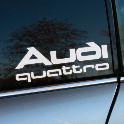 Plotrovaná nálepka s logom „Audi“ v modernom hranatom štýle a doplnkovým nápisom „quattro“, zdôrazňujúca športový pohon a identitu značky.