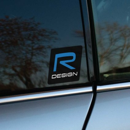 Tlačená nálepka „R DESIGN“ s modrým písmenom „R“ na elegantnom čiernom podklade. Prémiový dizajn pre vozidlá Volvo R-Design.