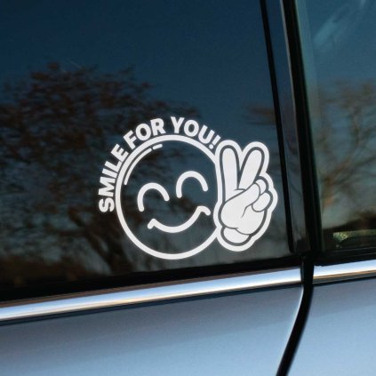 Plotrovaná nálepka na auto s usmievajúcim sa smajlíkom a gestom víťazstva, doplnená textom „Smile for you!“.