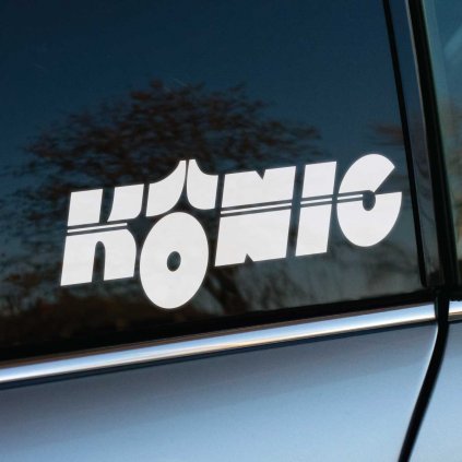 Biela nálepka „Konig“ s robustným a výrazným dizajnom, ktorý je doplnený charakteristickým grafickým prvkom pripomínajúcim korunu, nalepená na tmavom bočnom okne auta. Logo symbolizuje kvalitu a štýl značky Konig, známej výrobou prémiových diskov pre športové a tuningové vozidlá. Kontrast medzi bielou nálepkou a tmavým sklom zaručuje vynikajúcu viditeľnosť, pričom strieborná karoséria auta pridáva na sofistikovanosti a športovom vzhľade. Ideálne pre tuningových nadšencov a fanúšikov výnimočného dizajnu kolies.  Kľúčové slová: nálepka Konig, prémiové disky, tuningové doplnky, športové disky, nálepky na auto, personalizácia vozidla.