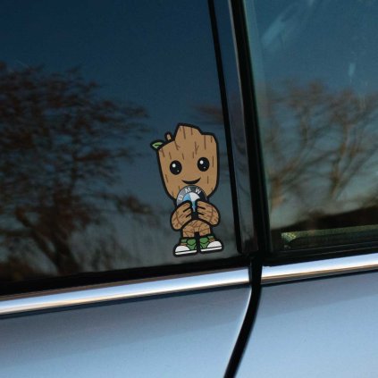 Tlačená nálepka postavičky baby Groot držiacej v rukách okrúhle logo značky BMW na čiernom podklade s bielym olemovaním.