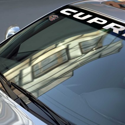 Sunstrip s veľkým bielym nápisom CUPRA v stredovej časti v detaile na čelnom skle strieborného vozidla značky BMW.