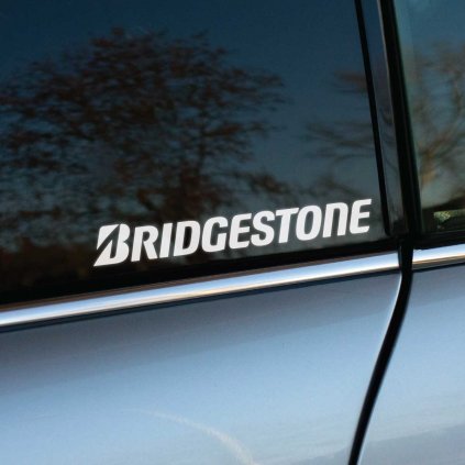 Biela nálepka s logom "Bridgestone" umiestnená na zadnom okne automobilu. Vynikajúci dizajn s čistými líniami podčiarkuje renomé tejto globálnej značky pneumatík a robí nálepku ideálnym doplnkom pre fanúšikov kvalitného automobilového príslušenstva. Nálepka je skvelým spôsobom, ako zvýrazniť podporu značke a dodať autu štýlový a profesionálny vzhľad.  **Kľúčové slová:** nálepka na auto Bridgestone, značkové nálepky Bridgestone, reklamné nálepky na auto, nálepky na okno auta, tuningové nálepky Bridgestone, polepy na auto, dizajn automobilových nálepiek, kvalitné nálepky na auto, nálepky pneumatík, doplnky na auto Bridgestone.