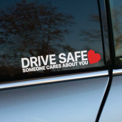 Plotrovaná nálepka s textom „Drive Safe Someone Cares About You“ a jednoduchým motívom srdca ako výzva k bezpečnej jazde.