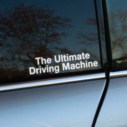 Plotrovaná nálepka pozostávajúca z čistého textového nápisu v dvoch riadkoch The Ultimate Driving Machine.