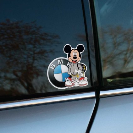 Tlačená nálepka s kreslenou postavičkou Mickey Mouse v teplákovej súprave, stojacou pred veľkým logom značky BMW.