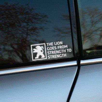 Plotrovaná nálepka s kráčajúcim levom v štvorci a nápisom THE LION GOES FROM STRENGTH TO STRENGTH v štyroch riadkoch.