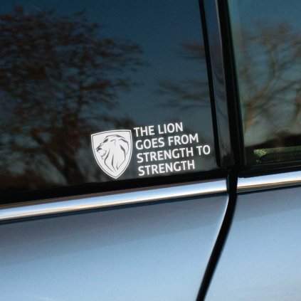 Plotrovaná nálepka s hlavou leva v štíte a nápisom THE LION GOES FROM STRENGTH TO STRENGTH v štyroch riadkoch vedľa.