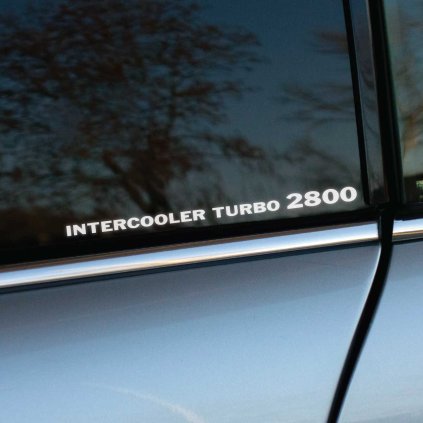 Plotrovaná nálepka s horizontálne orientovaným technickým nápisom v znení: INTERCOOLER TURBO 2800 s veľkým písmom.