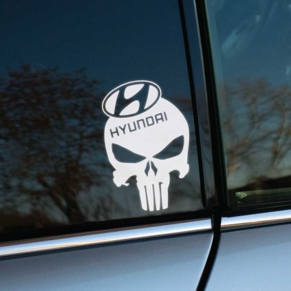 Biela Punisher lebka s logom Hyundai na vrchu, nalepená na bočnom okne auta. Táto nálepka spája ikonický symbol Punishera s moderným dizajnom a technológiou značky Hyundai, dodávajúc vozidlu odvážny a nezameniteľný vzhľad. Ideálna pre majiteľov Hyundai, ktorí chcú svojmu autu dodať trochu temného, no štýlového charakteru pomocou výraznej auto nálepky.