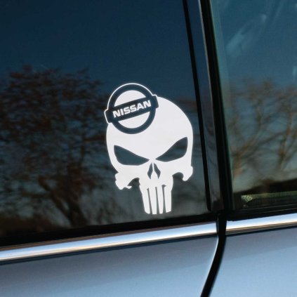 Na fotografii je bočný pohľad na automobil značky Nissan, na ktorom je nalepená biela nálepka s dizajnom lebky v štýle The Punisher, obsahujúca logo Nissan. Táto nálepka dodáva vozidlu agresívny a jedinečný vzhľad, ktorý upúta pozornosť na cestách. Ideálna dekorácia pre majiteľov automobilov Nissan, ktorí chcú svojmu autu dodať osobitý charakter a odlíšiť sa od ostatných.