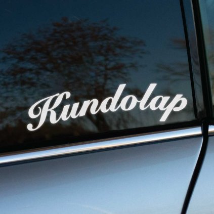 Na fotografii je biela nálepka s nápisom "Kundolap" v klasickom a elegantnom písme, nalepená na zadnom okne sivého auta. Tento štýlový font s ozdobnými krivkami vytvára jemne retro dojem, ktorý pridáva nálepke sofistikovaný vzhľad, aj napriek vtipnému obsahu nápisu. Kontrast medzi bielou farbou a tmavým oknom zaručuje, že je nálepka dobre viditeľná. Ideálna pre tých, ktorí chcú pridať svojmu autu osobitý a zábavný detail s dávkou elegancie.