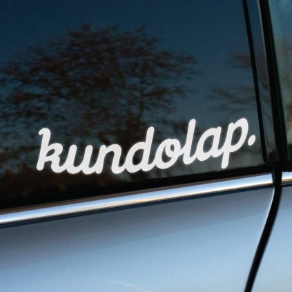 Nálepka s textom „kundolap“ v jemnom, bielom kurzívnom písme, nalepená na zadnom bočnom okne strieborného auta. Tento dizajn má provokatívny a humorný charakter, ktorý určite upúta pozornosť a pridá vozidlu jedinečný a štipľavý vzhľad. Ideálny pre tých, ktorí sa neboja ukázať svoju osobnosť a pridajú svojmu autu vtipný detail.
